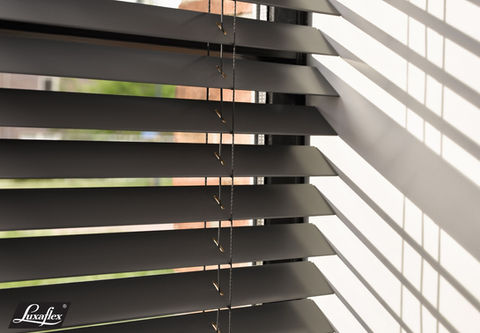 Dark venetian blinds casting striped shadows