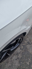 car body dent on the side, near tyre, of white car