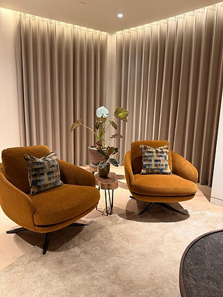 Two orange armchairs with cushions, small table, light curtains