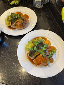 Two plates with a meal of meat, green vegetables, and sauce.