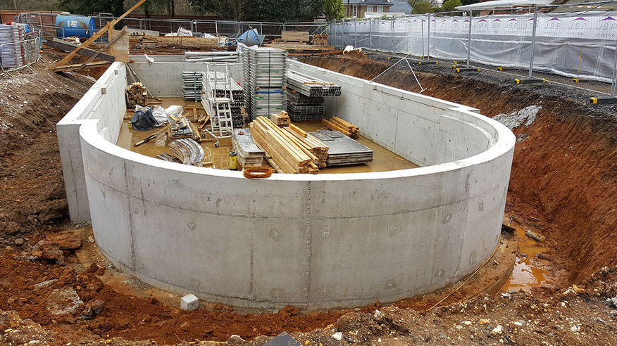 Partially built swimming pool with materials and scaffolding on-site.