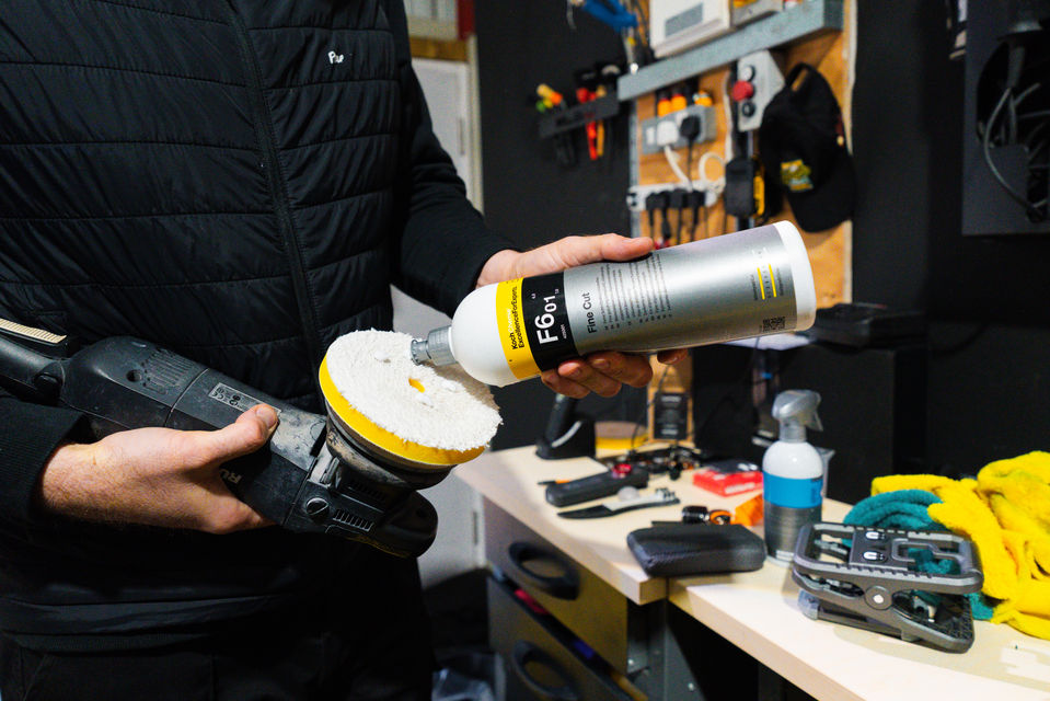 man applying solution to a car polishing machine