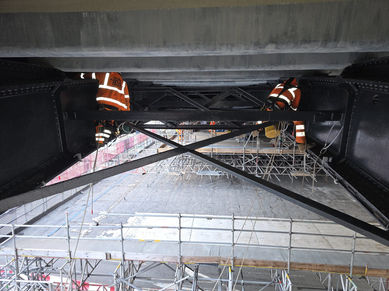 Workers on scaffolding under a bridge structure