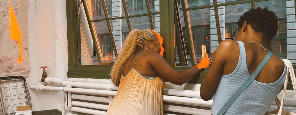 a person leaning out of a window so she can take a photo of the sunset