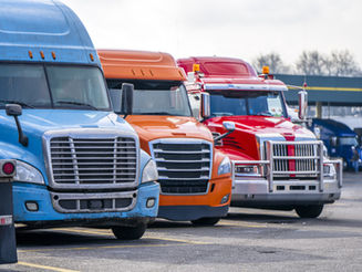 Row of colorful semi-trucks parked at a truck stop, representing the real-world parking challenges SpotHound aims to solve.