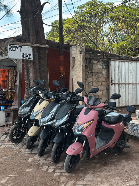 Electric scooters lined up for rental on a sandy street in Gili Air