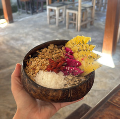 Smoothie bowl served in a coconut shell with fresh fruit and granola toppings at a cafe on Gili Air