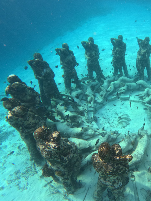 The famous underwater statue installation off the coast of Gili Meno, surrounded by clear blue water and small tropical fish.