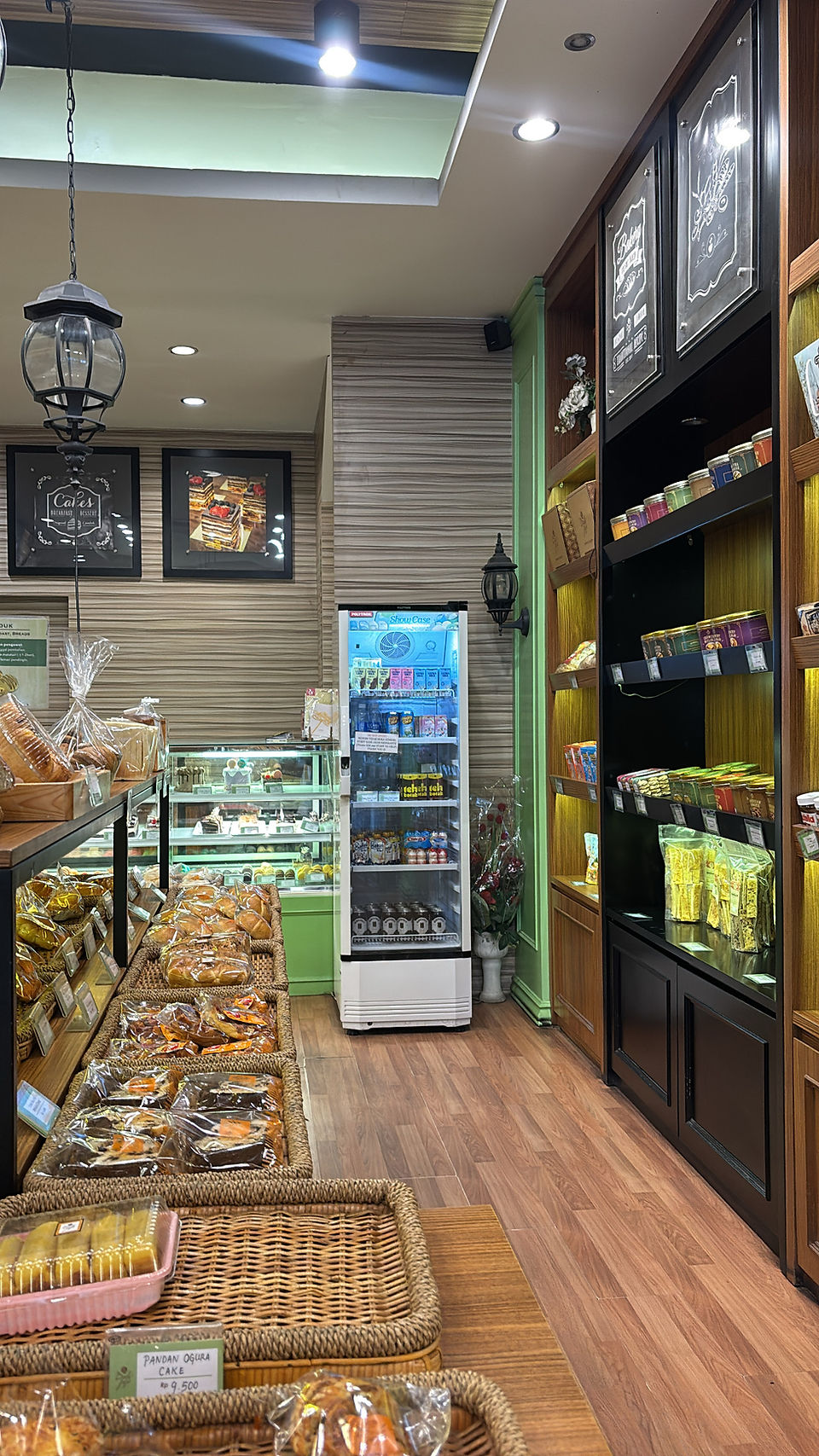 Warm interior of Bale Jajé Bakery in Lombok with wooden shelving, fresh baked goods, packaged treats, and a modern pastry display counter.