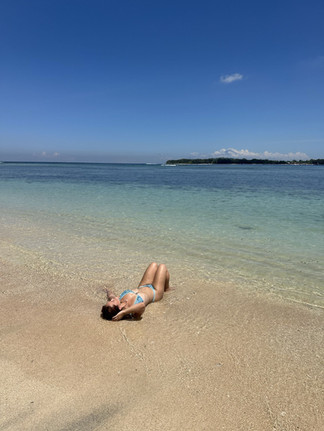 Woman relaxing in the shallow turquoise waters of Gili Trawangan on a sunny day.
