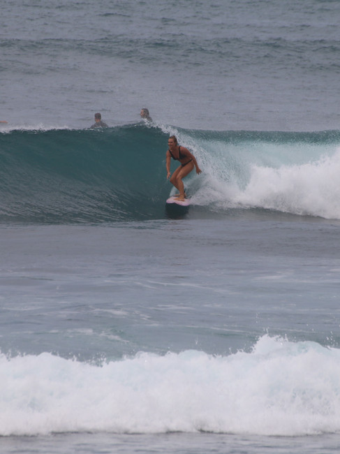 Female surfer riding a clean reef break wave near Kuta Lombok during a surf session