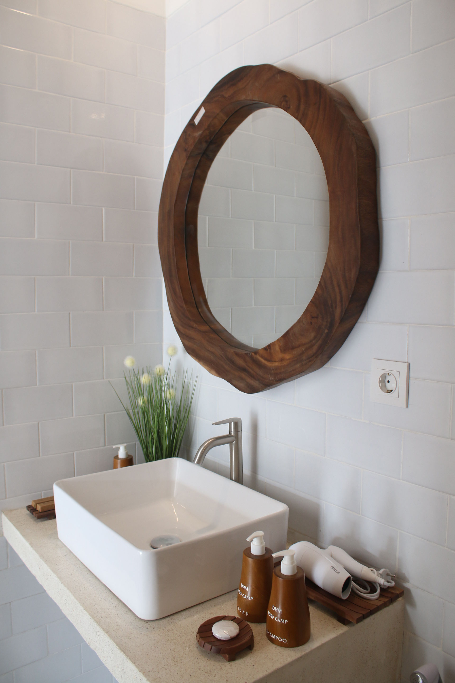 Modern ensuite bathroom at DHM Surf Camp featuring a white basin, clean finishes, and a round wooden mirror