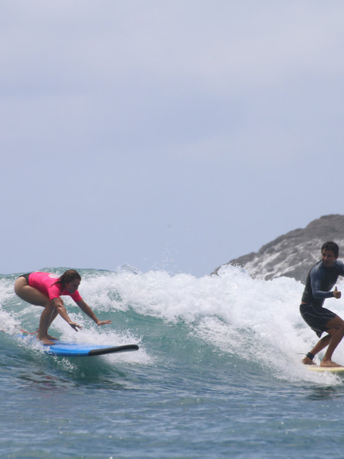 Surf instructor guiding a female student through a wave during a beginner surf lesson near Kuta Lombok