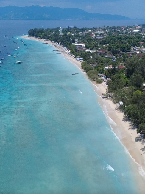 Aerial view of Gili Trawangan's white sand coastline and turquoise waters, a popular destination for beginner snorkeling and marine life encounters