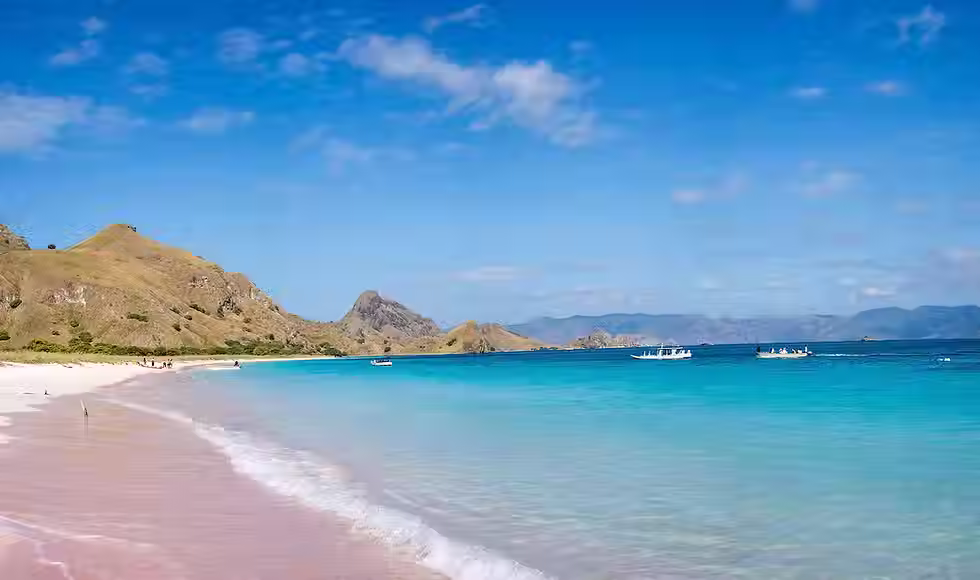 Pink sand beach with turquoise water and dive boats at Pink Beach Tangsi East Lombok Indonesia