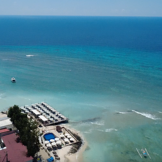 Aerial view of a beachfront resort surrounded by turquoise water in the Gili Islands.