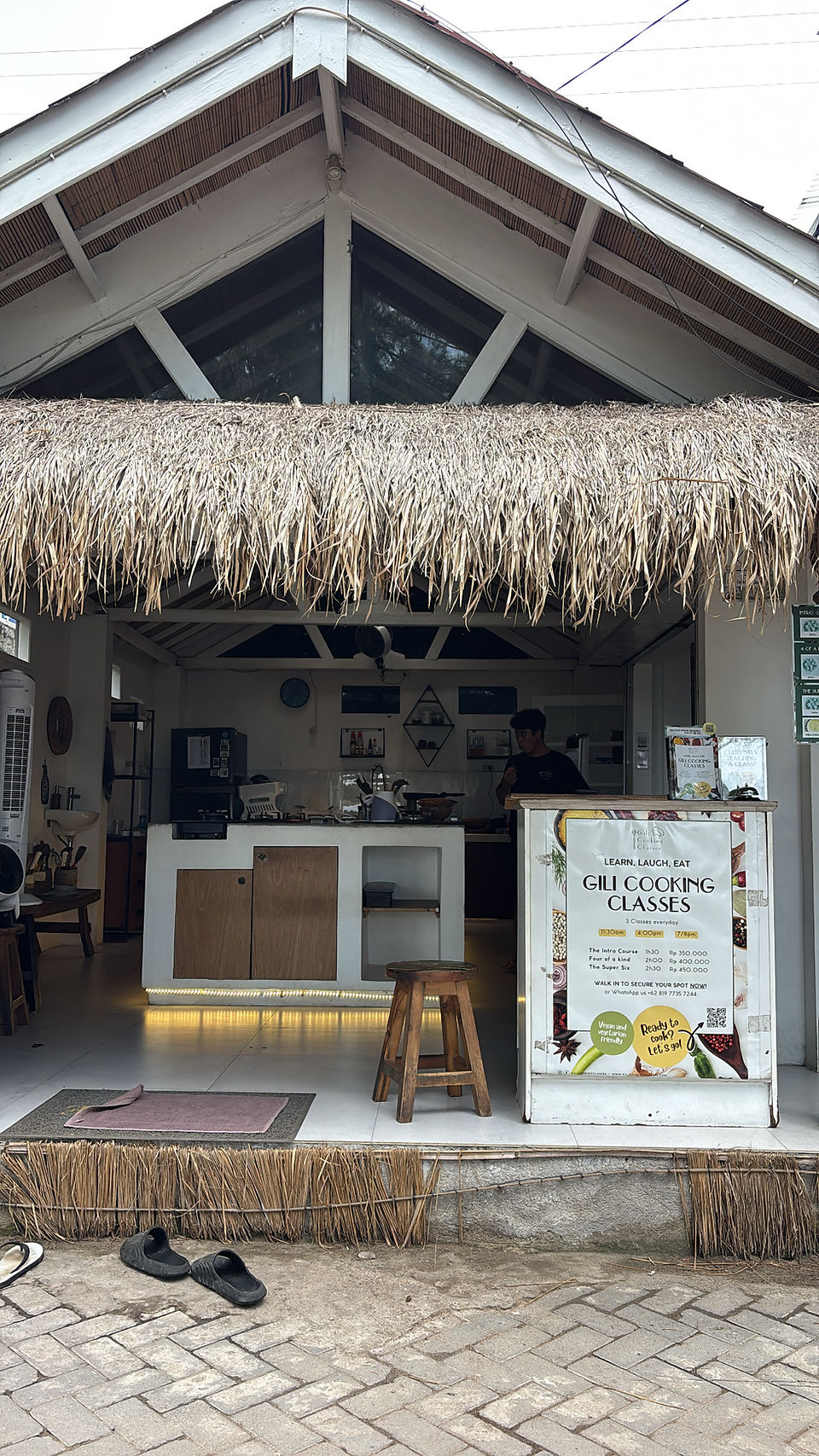 Open-front cooking class studio on Gili Trawangan with a thatched roof and sign for Gili Cooking Classes at the entrance.