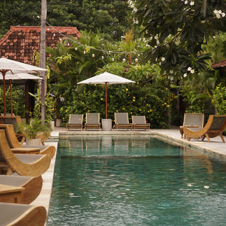 Boutique pool with timber sun loungers surrounded by tropical garden on the Gili Islands