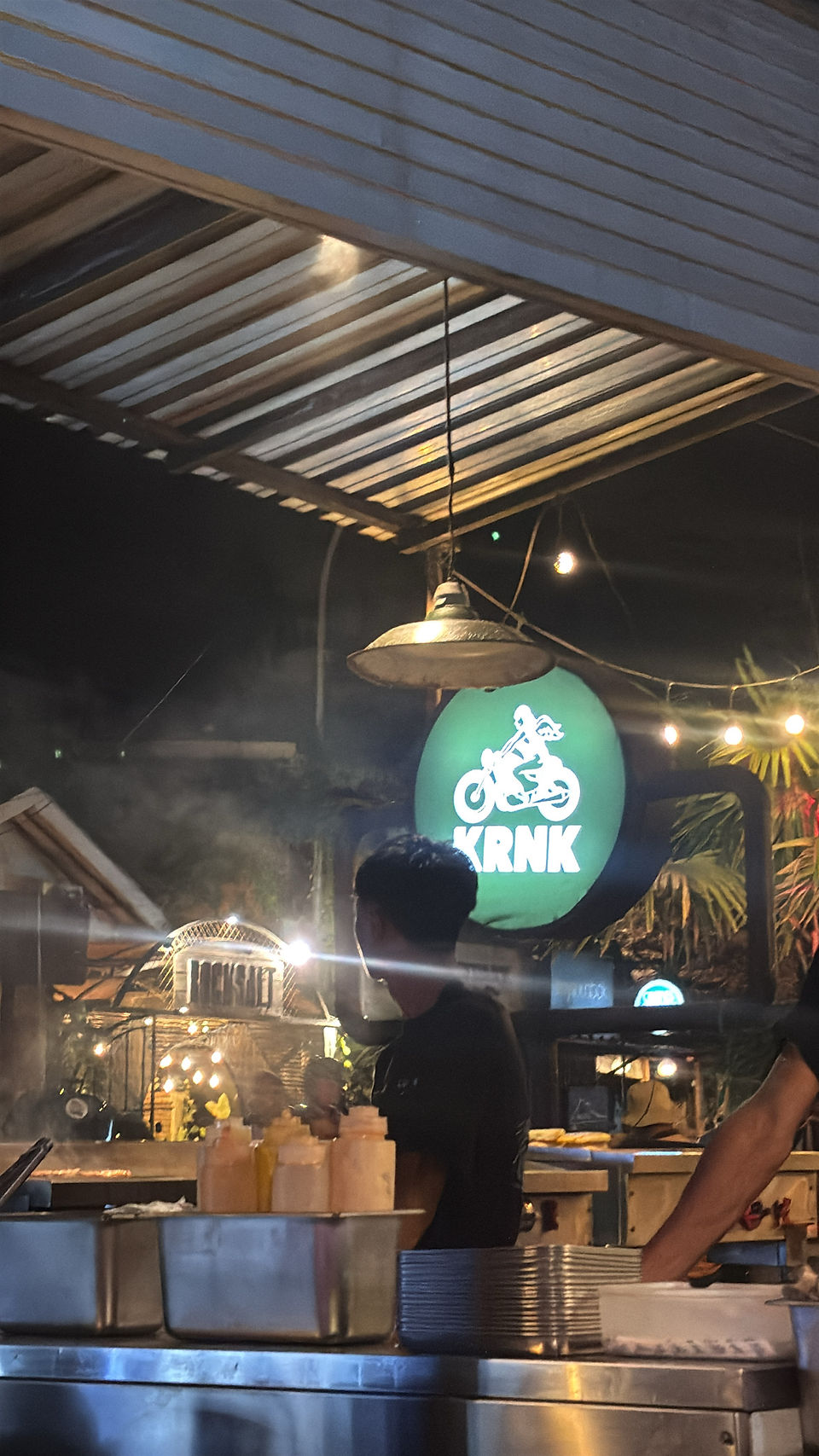 Illuminated KRNK restaurant logo above the open-air dining area in Kuta Lombok