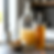 A professional editorial photograph on a minimalist kitchen counter featuring the components of mead making. In the center, a large glass carboy contains a pale, fermenting honey-water must, sealed with a clear plastic fermentation lock (airlock). To its right, a finished bottle of golden, clear mead with a black wax-sealed cork. In the foreground, a small ceramic bowl holds raw honeycomb and a wooden honey dipper. The lighting is bright and natural, creating a clean and artisanal aesthetic.