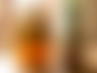 A large glass jar of fermenting tepache filled with pineapple peels and cinnamon sticks, placed on a wooden table next to a whole pineapple and a block of piloncillo sugar in a bright, natural setting.