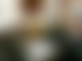 A bartender in a dark apron stands at a modern, well-lit cocktail station, carefully checking the label on a glass bottle.