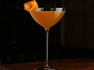 A perfectly double-strained Satan's Whiskers cocktail served in a chilled Nick and Nora glass.