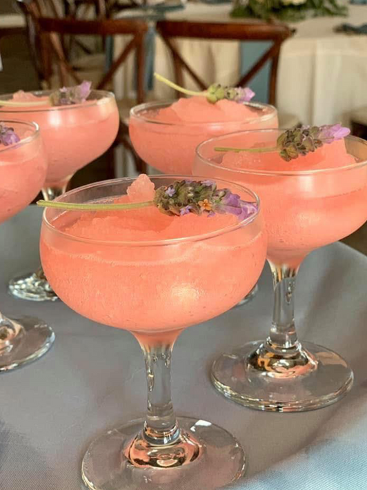 Refreshing pink frozen drinks in coupe glasses with lavender garnish.