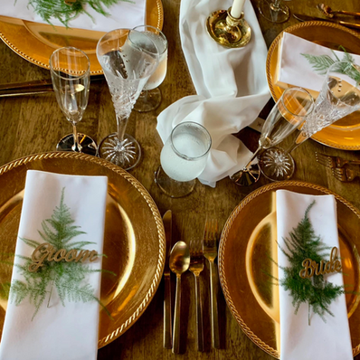 Festive golden wedding table settings with "Groom" and "Bride" place cards.