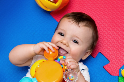 Smiling baby playing with a rattle toy