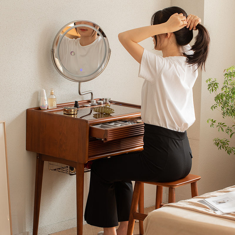 Woman tying her hair back while seated at the Ingrid Dressing Table, with the Halo MirrHalo Mirror, showing the mirror's larg