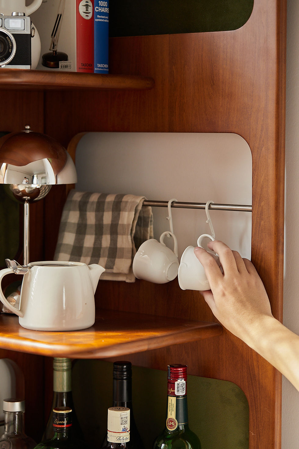 Thumbnail: Hooks detail Metal hooks under the Orbit corner shelf holding white checkered mugs