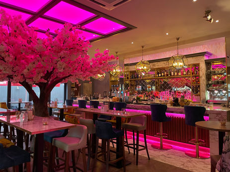Pink-lit bar with custom mirrors and glass surfaces fitted by Hurry Bros for a bold, premium aesthetic.