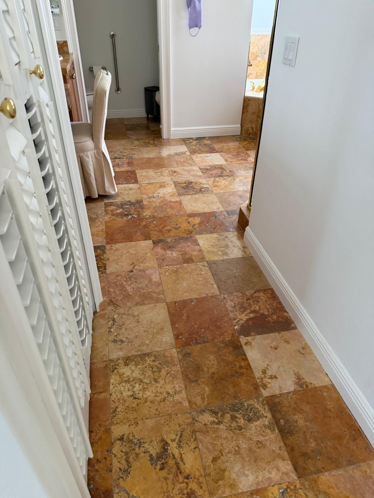 Brown and tan checkered tiled hallway floor leading to another room.