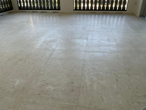 Light beige tiled floor in an empty room with dark grilles.