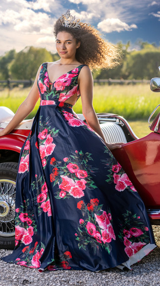 Senior prom queen wearing floral prom dress with red convertible in senior portraits