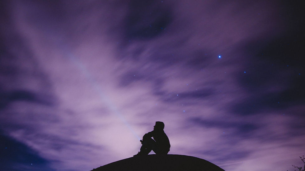 A lone figure gazes up at a starry night sky, silhouetted against swirling, illuminated clouds.