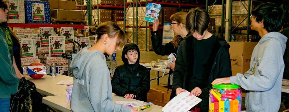 Volunteers for Kidzz Helping Kidzz communicating in an assembly line structure while making work fun.