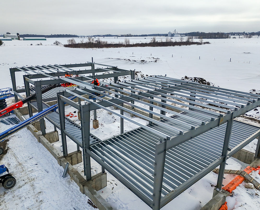 Steel building frame under construction in a snowy land scape .