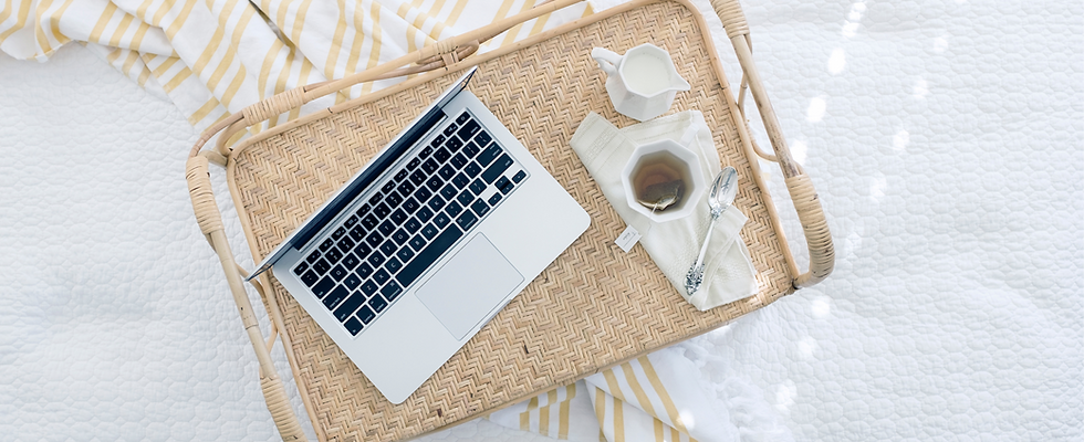 A laptop on a bed with a cup of tea conveying the use of the laptop for online therapy in a comfortable and calm setting