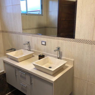 Baño con tocador en mármol crema marfil y muebles en melamina crema y lavatorios tipo bowl en mármol especialmente elegidos 
