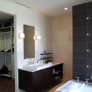 Tocador minimalista con sobre blanco en mármol, gabinetes de madera oscura y accesorios de baño modernos marca Kohler