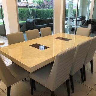 Comedor minimalista en mármol crema y sillas de cuero elegidas especialmente para los clientes 