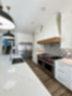 Modern farmhouse kitchen with white cabinets and wood hood
