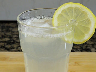 Foto de la limonada, que tiene una rodaja de limon en el borde del vaso