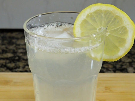 Foto de la limonada, que tiene una rodaja de limon en el borde del vaso