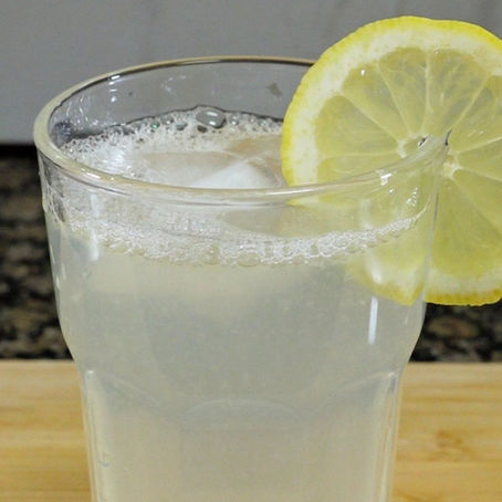 Foto de la limonada, que tiene una rodaja de limon en el borde del vaso