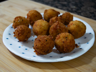 Bolitas de pollo y queso rebozadas sobre un plato blanco con puntos azules