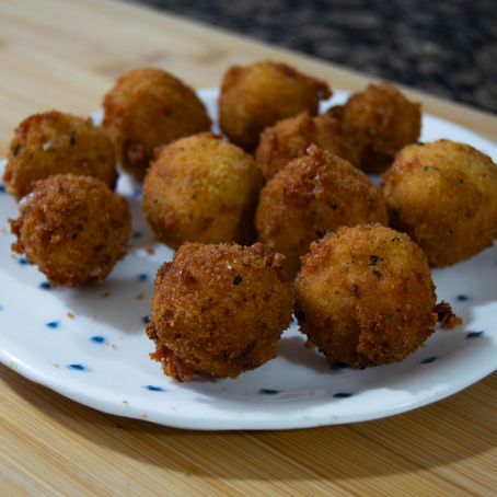 Bolitas de pollo y queso rebozadas sobre un plato blanco con puntos azules