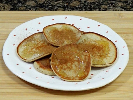 Foto de las tortitas amontonadas sobre un plato pequeño, y una tabla de madera de fondo